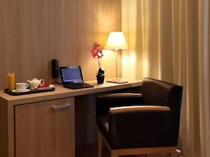 A hotel room with a wooden desk, a laptop, a lamp, a chair, and a small potted plant. - Lleo (Barcelona)