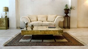 A living room with a beige sofa, a coffee table, a lamp, and a potted plant. - Hotel María Luisa (Burgos)