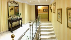 A grand hallway with a marble staircase, a large mirror, and framed botanical prints on the walls. - Hotel María Luisa (Burgos)