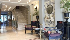 A spacious lobby with a marble floor, a staircase, and a seating area with chairs and a table. - Hotel María Luisa (Burgos)