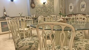 Un comedor con mesas y sillas redondas, un reloj decorativo de pared y un papel tapiz estampado.