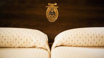 Una cama con cabecera de madera y un emblema dorado con el texto "HOTEL" y "MANTA HAYA".