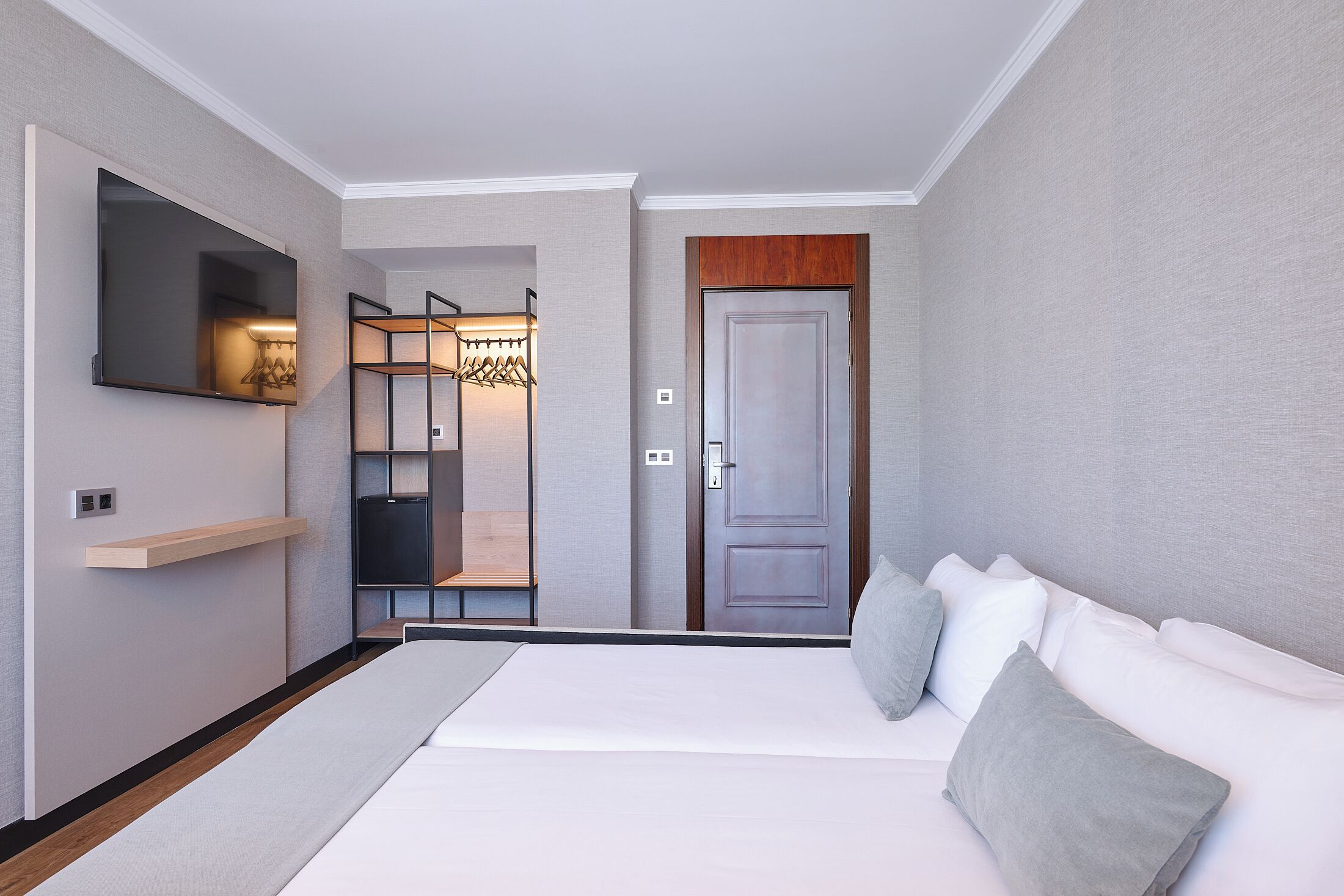 Een moderne hotelkamer met een groot bed, een tv die aan de muur is bevestigd, een kledingkast en een spiegel.