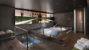 Un espacio de spa con un jacuzzi, una piscina y un mural de un edificio.