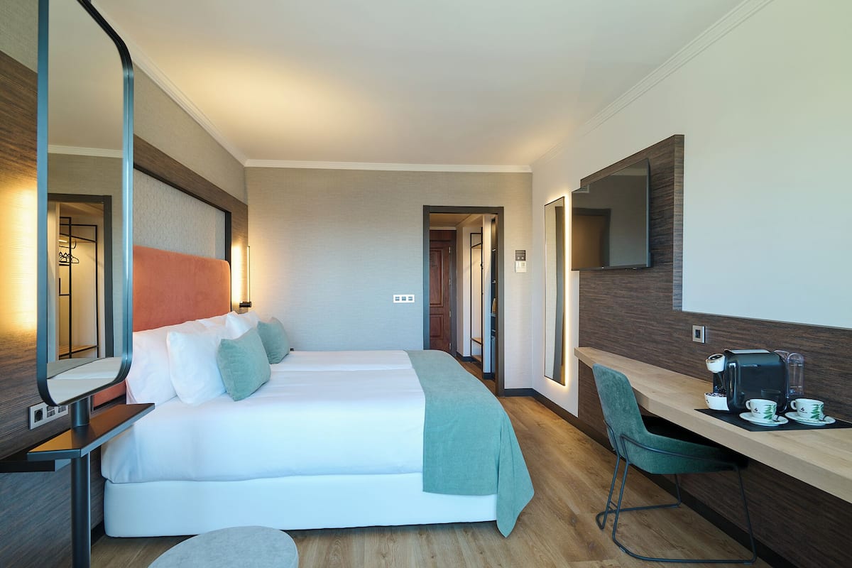 Een hotelkamer met een bed, een bureau met een koffiezetapparaat en een stoel.