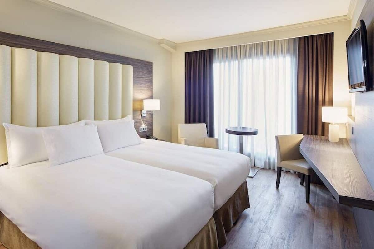 Een hotelkamer met een groot bed, nachtkastjes, een bureau, een stoel en een televisie.