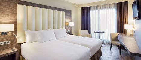Een hotelkamer met een groot bed, nachtkastjes, een bureau en een stoel.