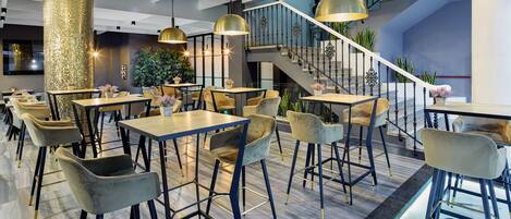 A modern restaurant with high ceilings, a staircase, and a mix of seating arrangements.