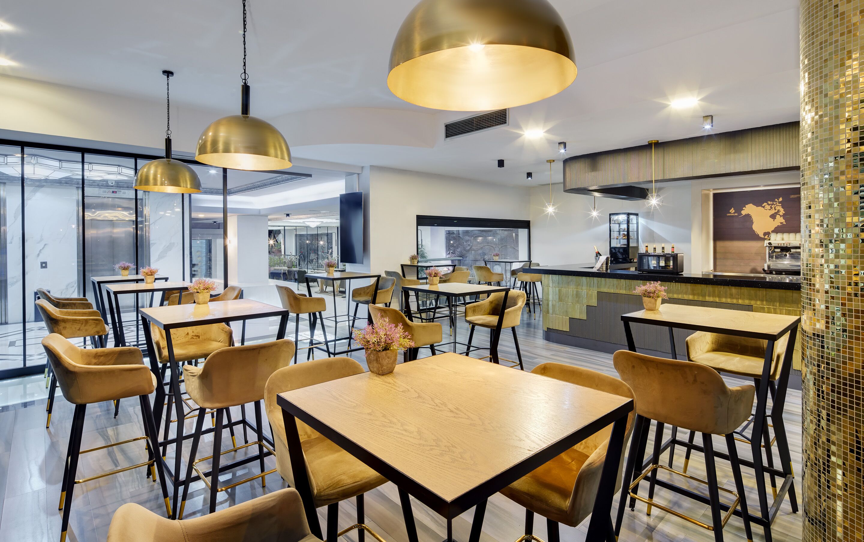 Un restaurante moderno con mesas y sillas altas, iluminación colgante y una zona de bar.