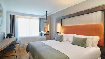 A hotel room with two beds, a desk, and a chair.
