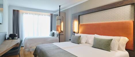 A hotel room with two beds, a desk, and a chair.