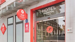A hotel entrance with signage for 'HOTEL MAGISTRAL' and 'exe MAGISTRAL' with a glass facade and red accents. - Exe Hotel El Magistral (Oviedo)
