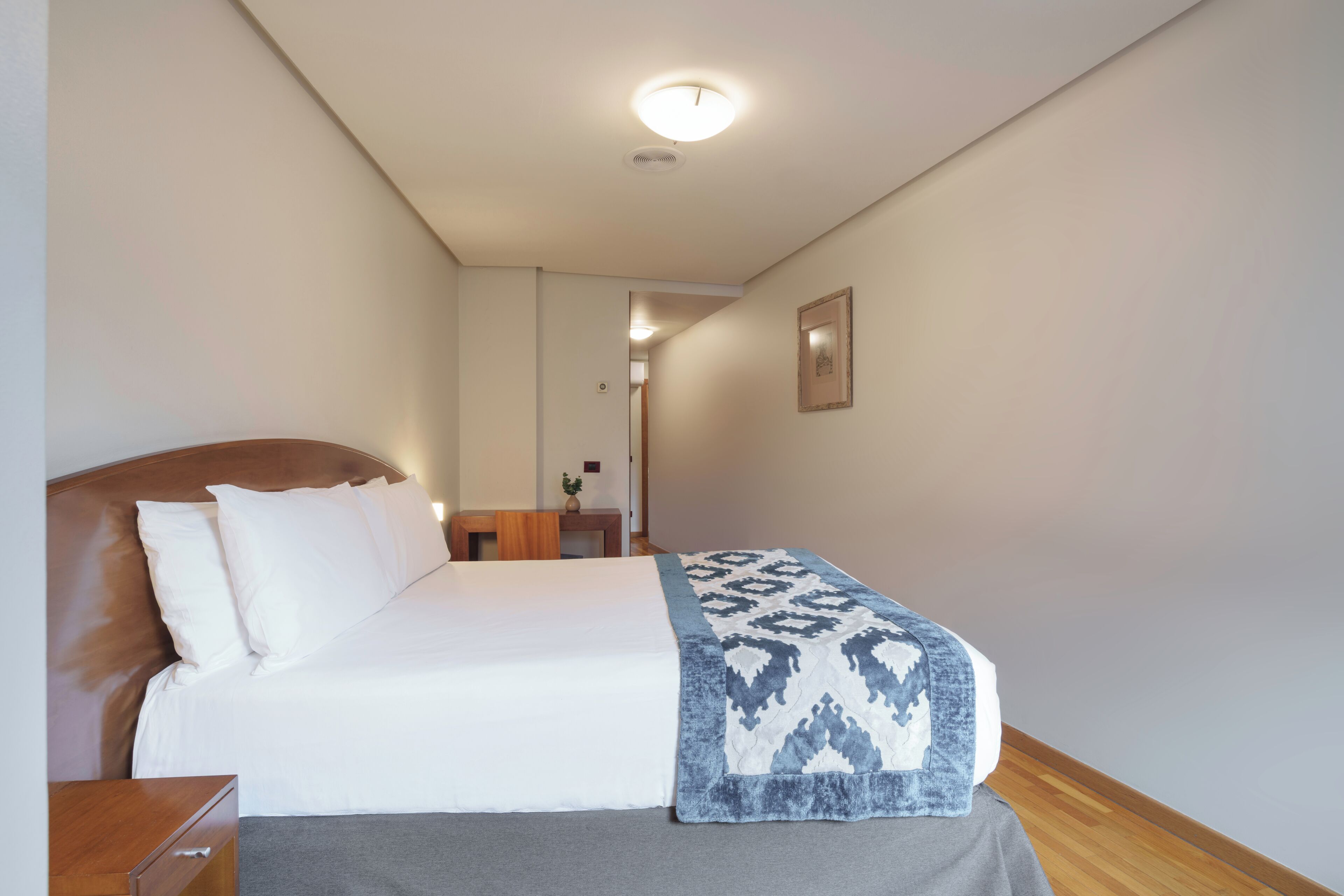 Una habitación de hotel con cama, mesita de noche y mesilla.