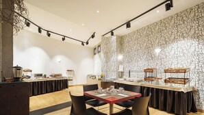 A modern dining area with a long table, black chairs, and a stone-patterned wall. - Exe Hotel El Magistral (Oviedo)