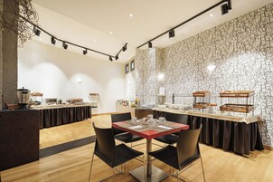 Un comedor moderno con una larga mesa, sillas negras y una pared con diseño de piedra.