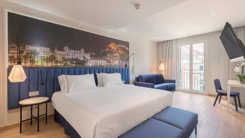 Una habitación de hotel moderna con una cama grande, zona de estar, escritorio y vistas a la ciudad.