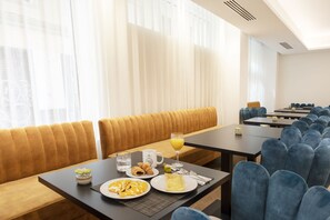 Une table, des chaises et un canapé disposés dans un coin repas moderne, créant un espace accueillant pour le petit-déjeuner.