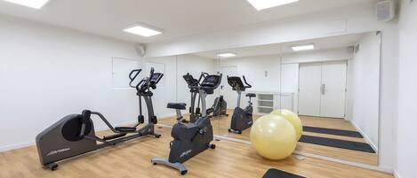 A gym with cardio machines, exercise balls, and mats.