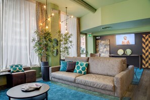A cozy lounge area with a sofa, a coffee table, and a television screen. - Best Western Plus CHC Florence (Florence)