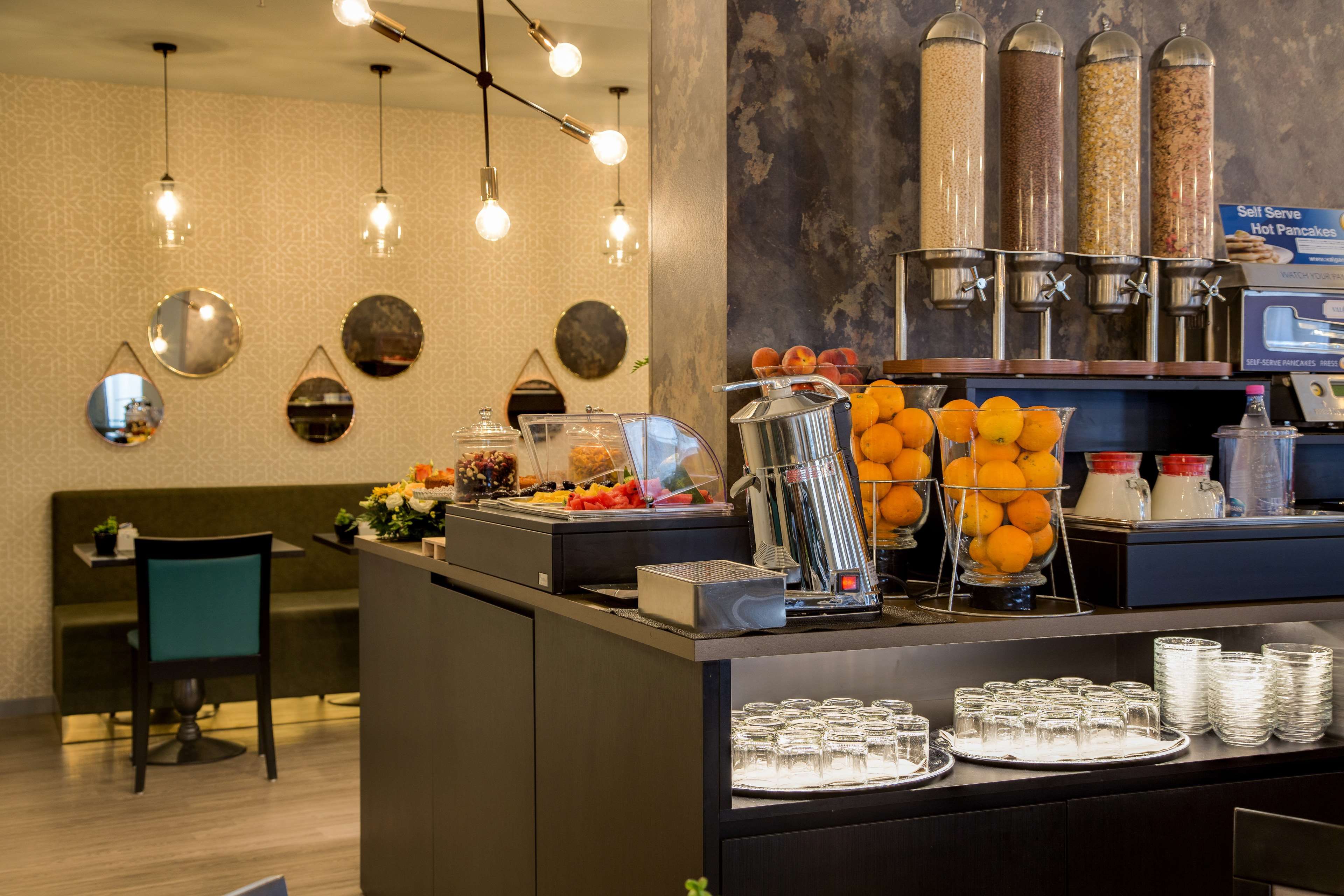 A self-serve breakfast station with various food options, including fruits and cereals.