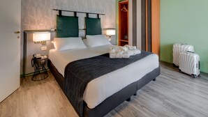 A hotel room with a large bed, bedside lamps, a wardrobe, and two suitcases. - Best Western Plus CHC Florence (Florence)