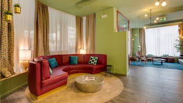 Ein modernes Wohnzimmer mit einem roten Modulsofa, einem runden Couchtisch und einem gemusterten Boden.