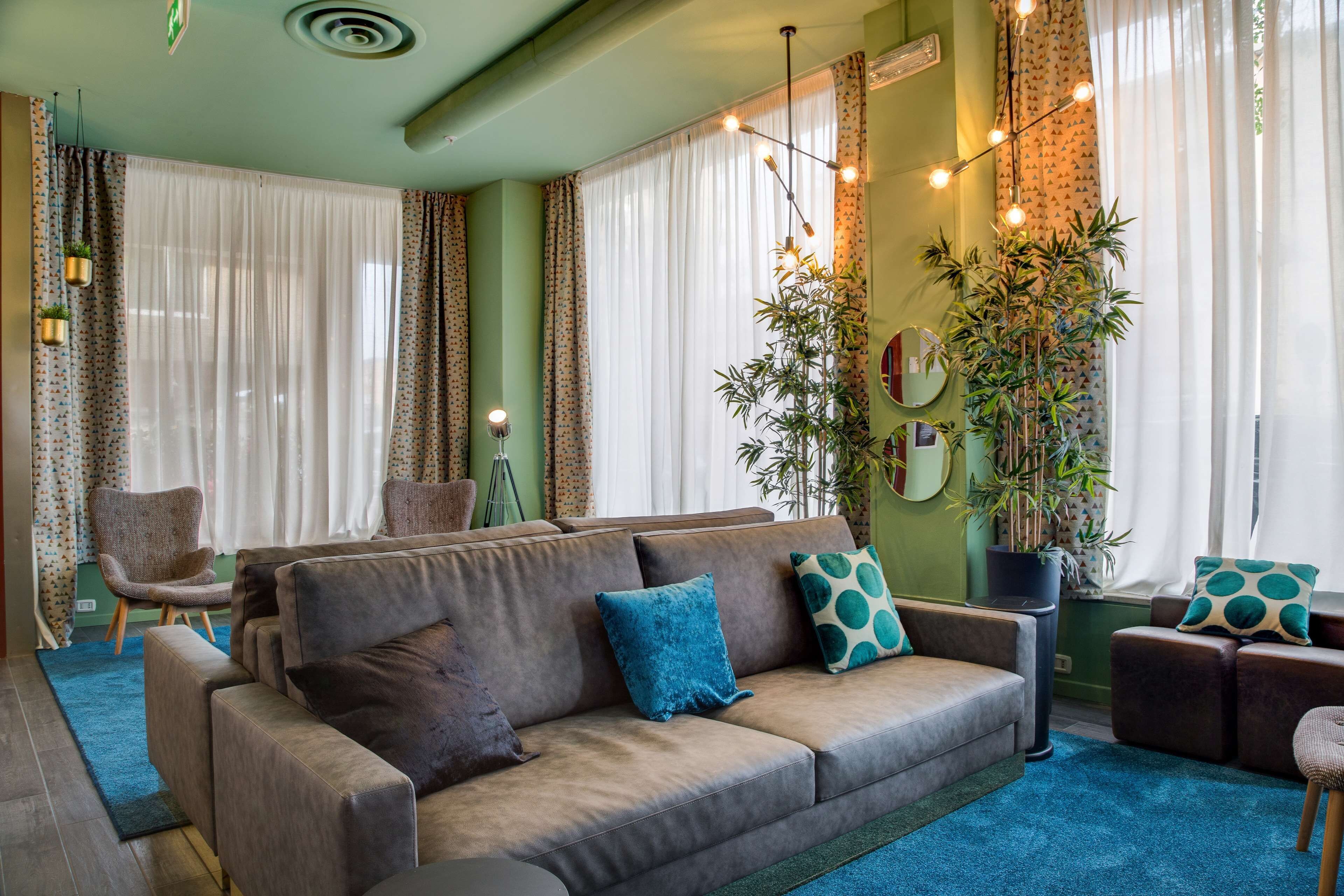 Ein Wohnzimmer mit einer Couch, Sesseln, einem Couchtisch und einer großen Kübelpflanze.