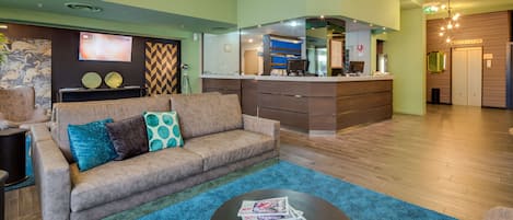 A modern hotel lobby with a sofa, a coffee table, and a reception desk.