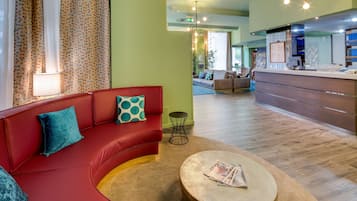 Ein modernes Wohnzimmer mit einem roten Sofa, einem runden Couchtisch und einem Essbereich mit einer Bar.