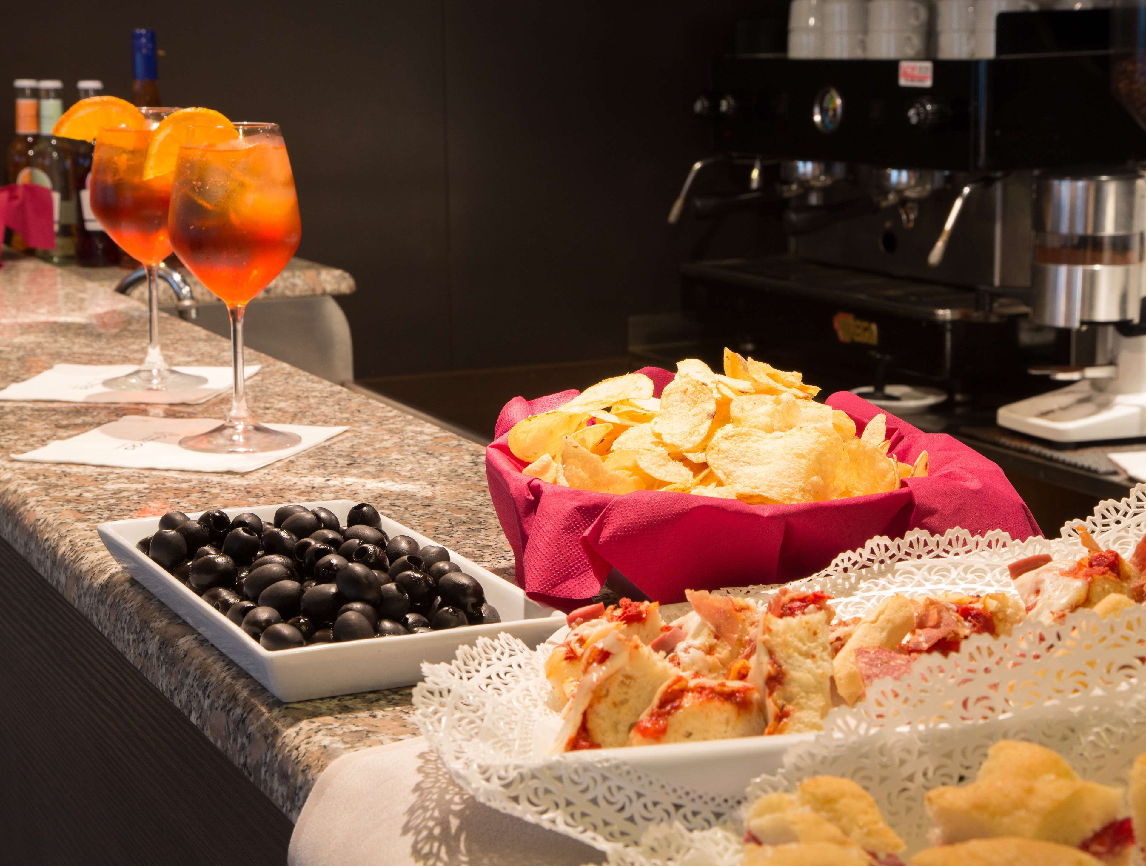 A buffet setup with a variety of food items including olives, chips, and bread.