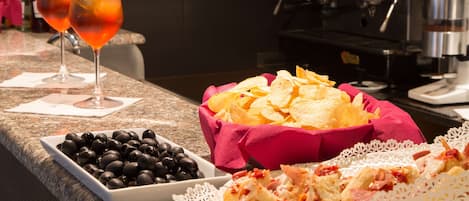 A buffet setup with a variety of food items including olives, chips, and bread.