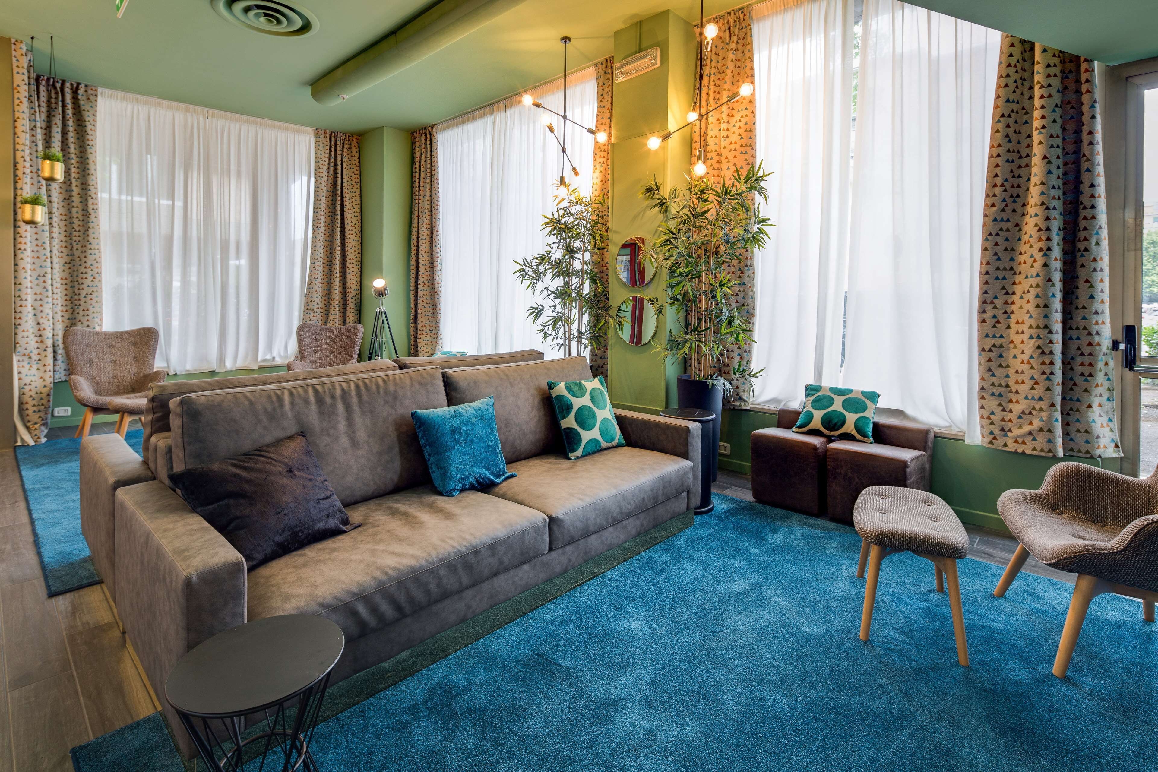 Ein gemütliches Wohnzimmer mit einer Couch, Sesseln, einem kleinen Tisch und einer großen Pflanze.