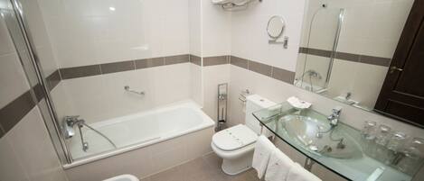 A modern bathroom with a glass-enclosed shower, a glass sink, and a toilet.