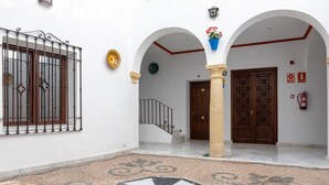 Un patio con suelo de baldosas, una escalera y una puerta de madera.