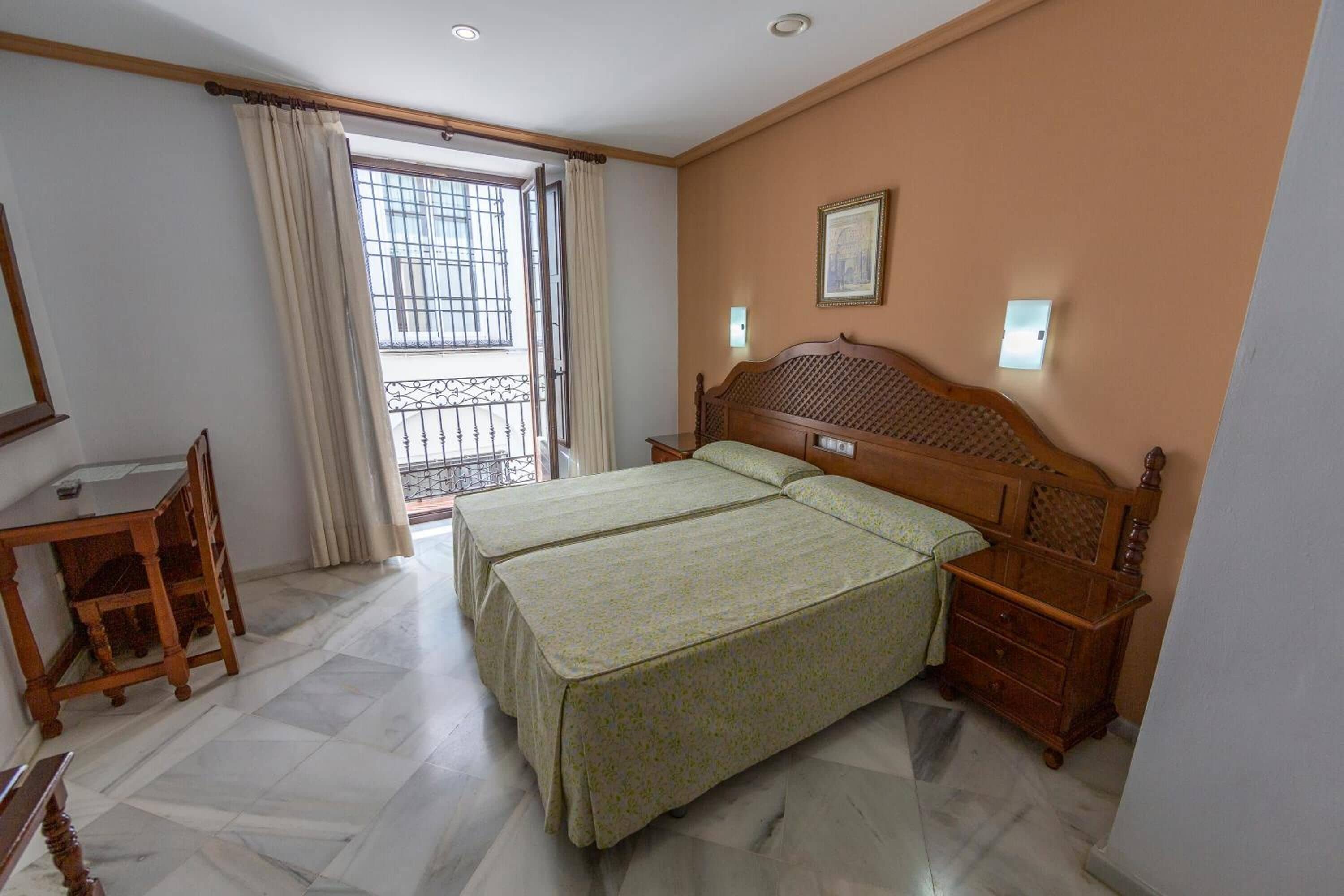 Une chambre d’hôtel avec deux lits, une table de chevet en bois, un bureau et une chaise.