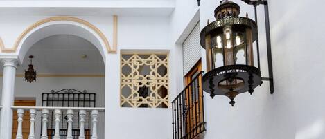 A white building with a balcony, a decorative lantern, and a patterned window.