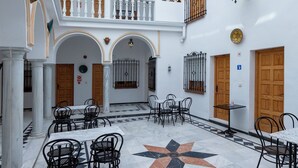 Un patio amplio con paredes blancas, piso de baldosas y varias zonas de estar.