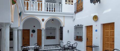 A spacious courtyard with white walls, a tiled floor, and multiple seating areas.