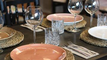 Una mesa dispuesta con platos, vasos y cubiertos, con individuales tejidos.