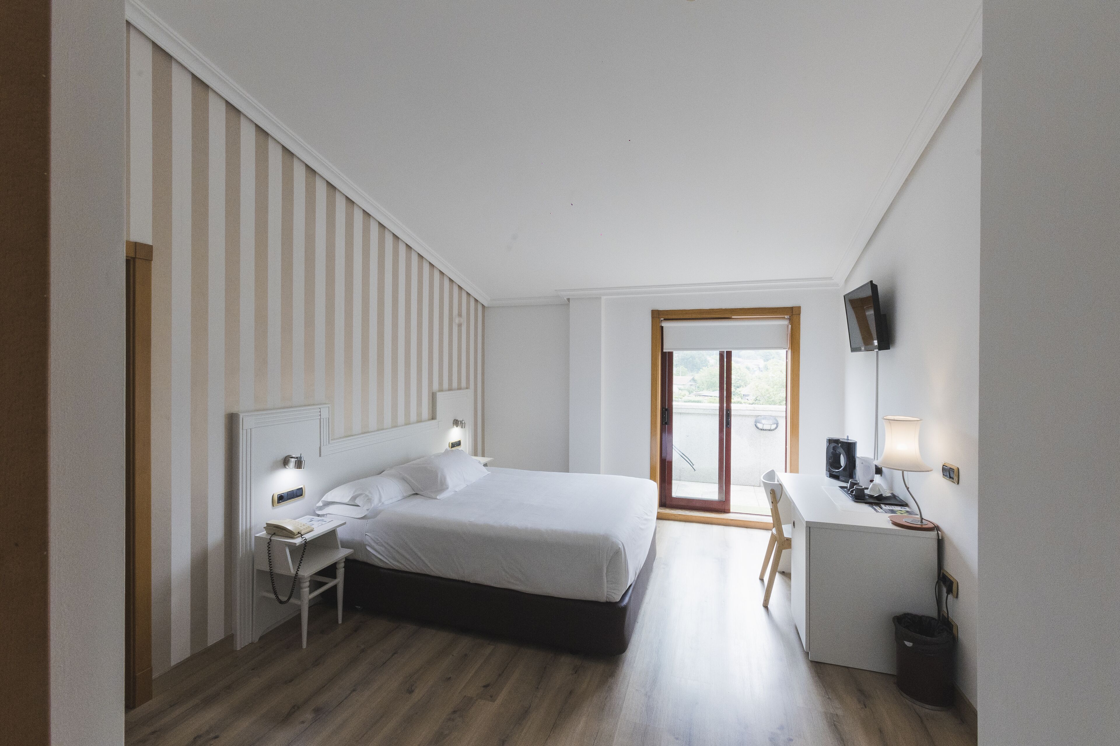 Una habitación de hotel moderna con una cama grande, un escritorio y una televisión.