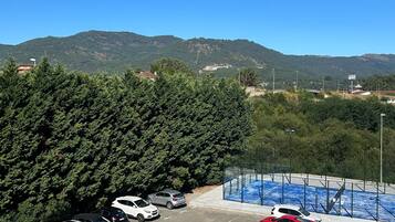 Un estacionamiento con varios autos, un auto deportivo azul y un letrero que indica un hotel.