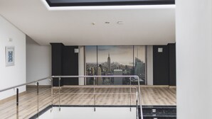 Een moderne kamer met uitzicht op de stad, een houten vloer en een metalen hekwerk.