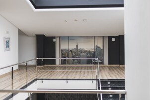 Una habitación moderna con vistas a la ciudad, piso de madera y barandilla metálica.