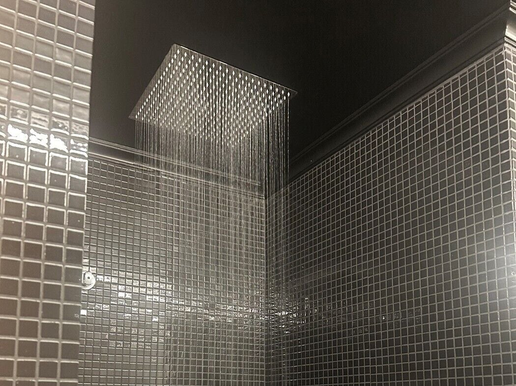 A bathroom with a tiled wall and a shower area.