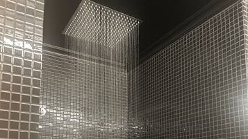 A bathroom with a tiled wall and a shower area.