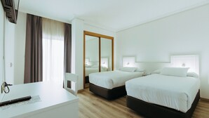 Een hotelkamer met twee bedden, een bureau en een spiegel.