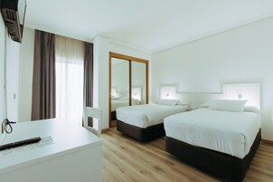 Habitación de hotel con dos camas, un escritorio y un espejo.