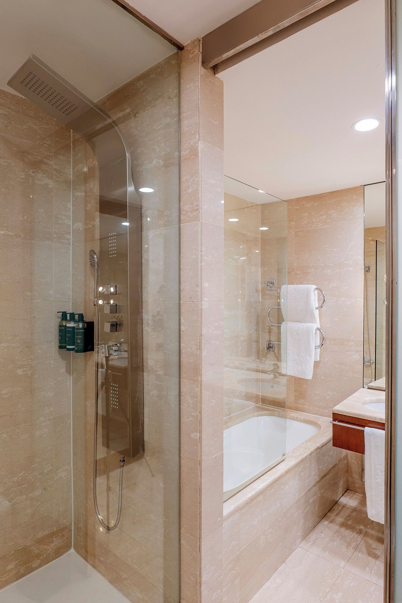 Un baño moderno con ducha de vidrio, bañera y tocador con espejo.
