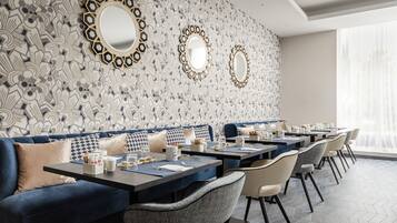 Un comedor moderno con pared decorativa, asientos azules y varias mesas.