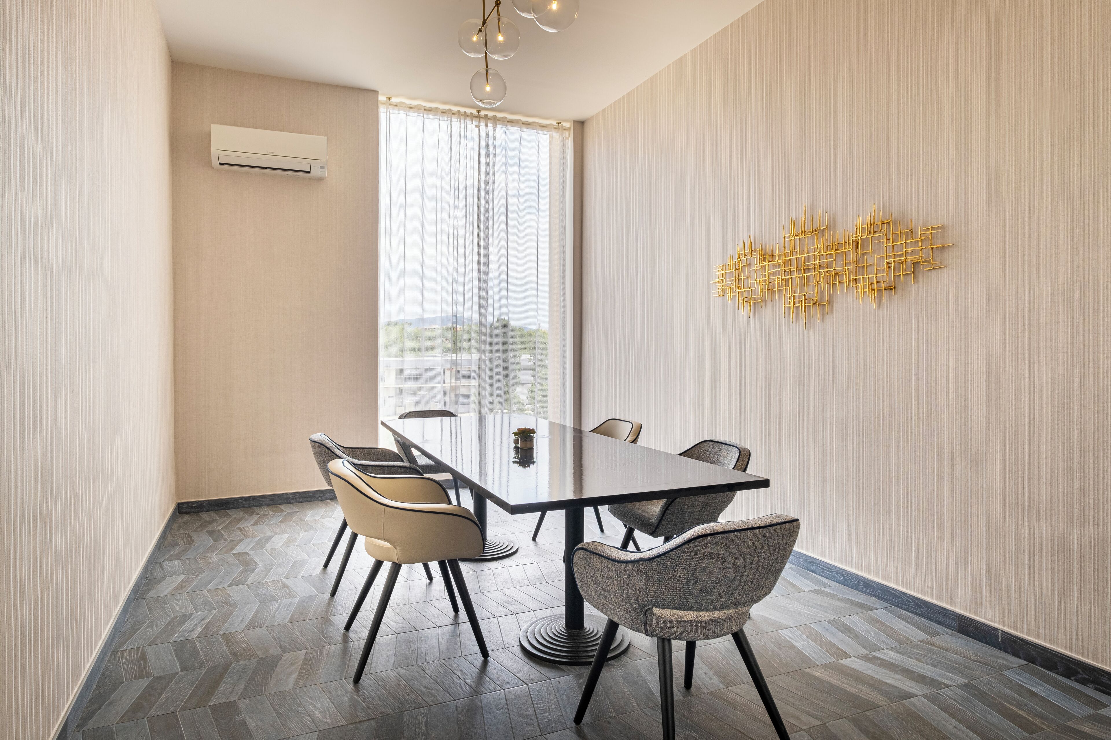 A modern conference room with a glass partition, a large table, and four chairs.